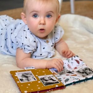 Bébé 6 mois qui lit un livre doudou